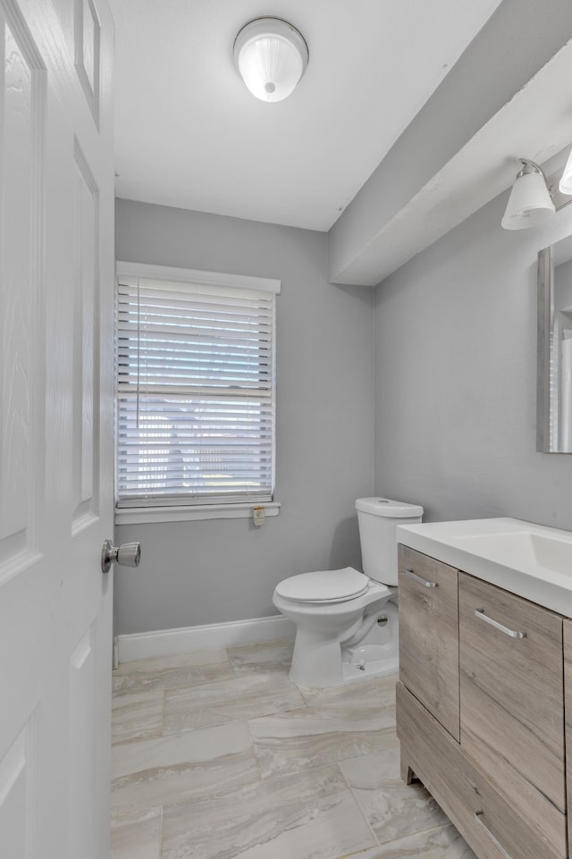 bathroom with toilet, marble finish floor, baseboards, and vanity