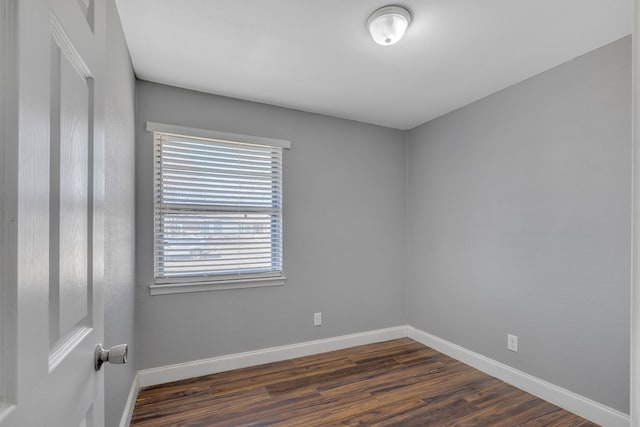 unfurnished room featuring dark wood-type flooring and baseboards