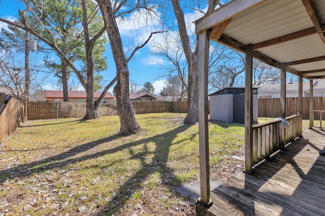 view of yard with a storage shed, a fenced backyard, a wooden deck, and an outdoor structure