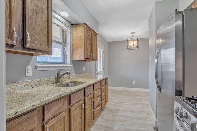 kitchen featuring light stone countertops, appliances with stainless steel finishes, brown cabinets, and a sink