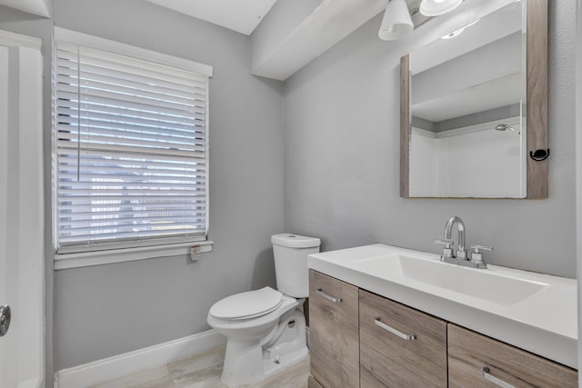 bathroom with toilet, baseboards, and vanity