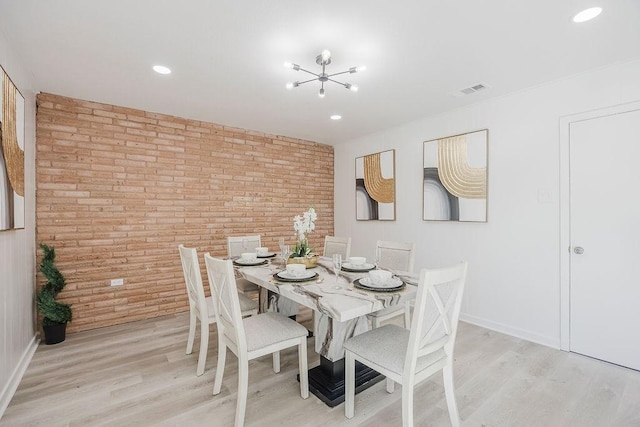 dining room featuring baseboards, brick wall, visible vents, and light wood-style floors