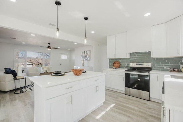 kitchen with electric stove, light countertops, decorative backsplash, light wood-style floors, and white cabinets