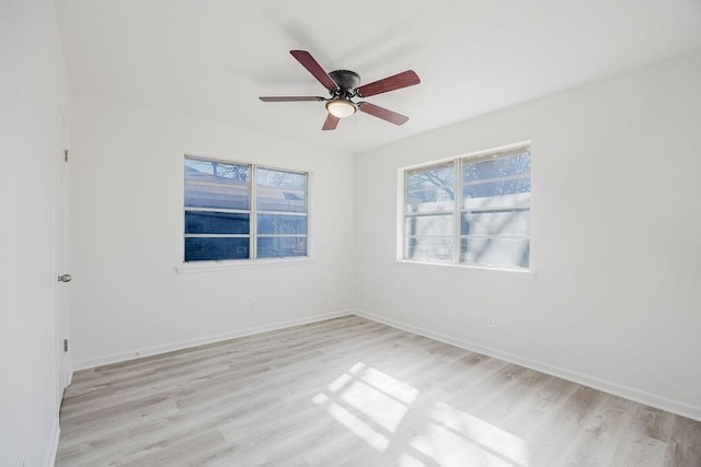 spare room featuring light wood finished floors, plenty of natural light, and baseboards