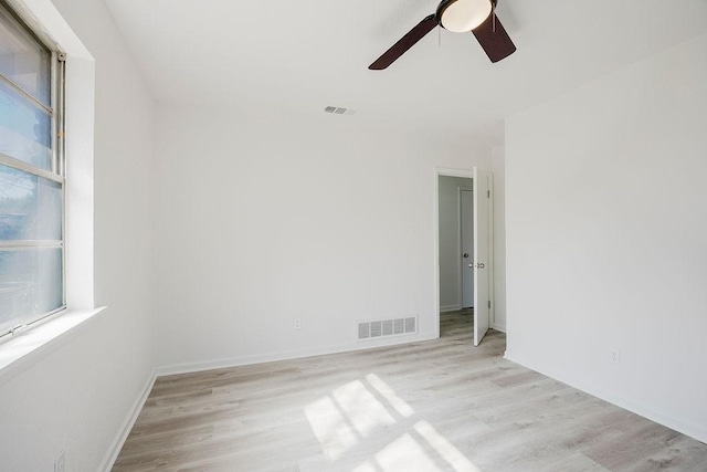 spare room with a ceiling fan, light wood-style flooring, visible vents, and baseboards