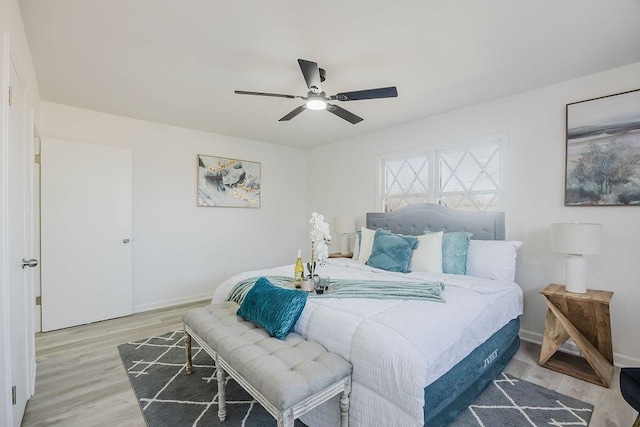 bedroom featuring a ceiling fan, light wood-style flooring, and baseboards