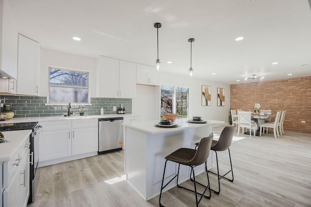 kitchen with a sink, stainless steel appliances, light wood finished floors, and light countertops