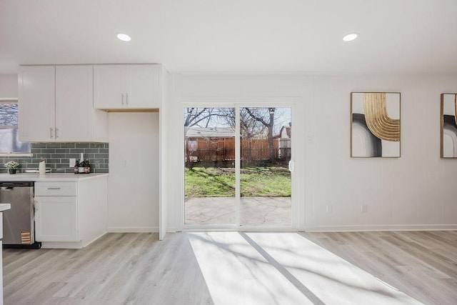 unfurnished dining area with baseboards, light wood finished floors, and recessed lighting