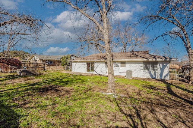 exterior space featuring a yard, brick siding, fence, and central AC unit