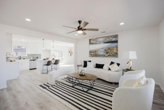 living area with visible vents, light wood finished floors, a ceiling fan, and recessed lighting