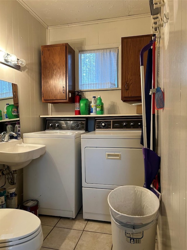 clothes washing area with washing machine and dryer, crown molding, and light tile patterned floors