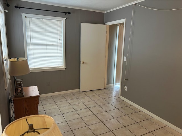 empty room with crown molding, baseboards, and light tile patterned floors