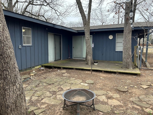 back of house with a deck, an outdoor fire pit, and board and batten siding