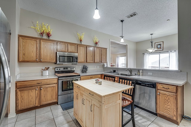 kitchen with visible vents, appliances with stainless steel finishes, a kitchen breakfast bar, a peninsula, and a sink