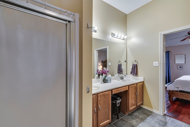 ensuite bathroom with double vanity, baseboards, a ceiling fan, ensuite bath, and a sink