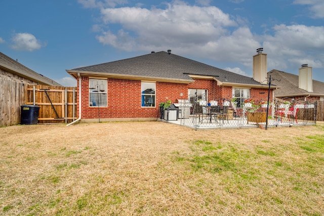 back of house with a yard, a fenced backyard, a patio, and brick siding