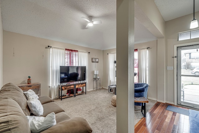 living room with ceiling fan, a textured ceiling, baseboards, and wood finished floors