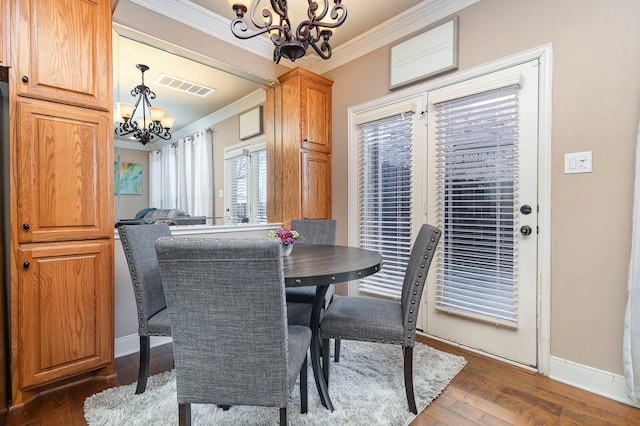 dining area featuring crown molding, dark wood finished floors, a notable chandelier, visible vents, and baseboards