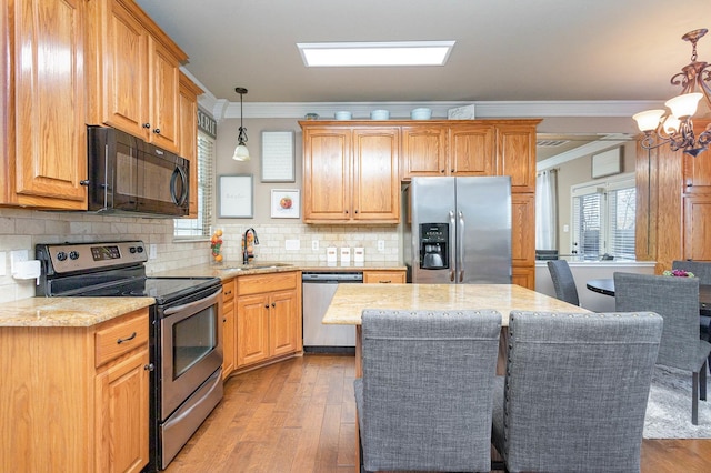 kitchen with light wood finished floors, appliances with stainless steel finishes, and crown molding