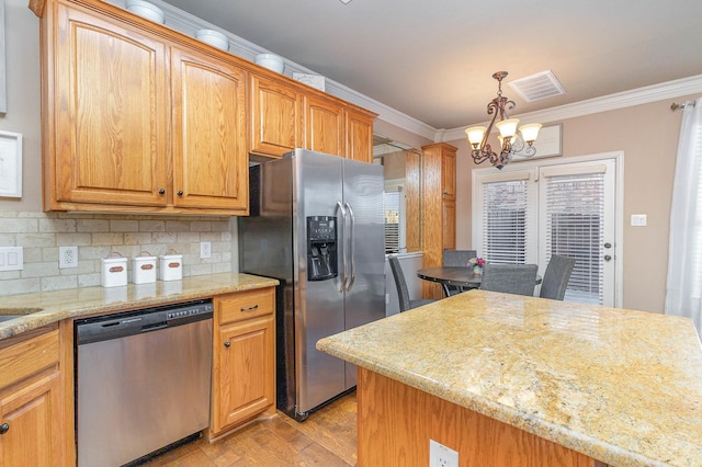 kitchen featuring a notable chandelier, tasteful backsplash, appliances with stainless steel finishes, ornamental molding, and light wood-type flooring