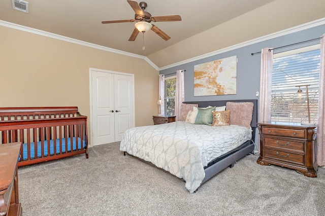 bedroom with carpet, lofted ceiling, a closet, visible vents, and ornamental molding