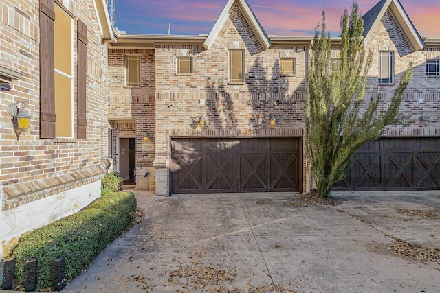 view of front of house featuring driveway, an attached garage, and brick siding