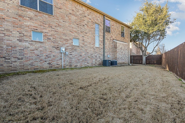 rear view of property featuring brick siding, a lawn, and a fenced backyard