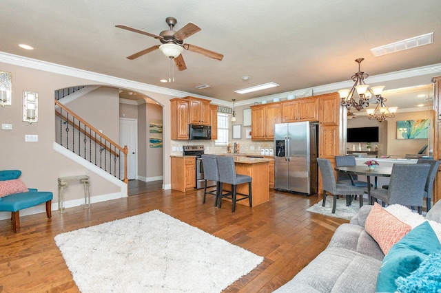 living room featuring stairs, visible vents, wood finished floors, and ornamental molding