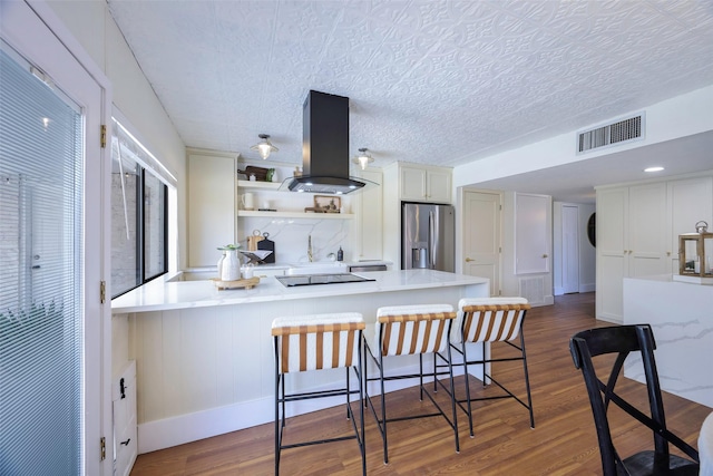 kitchen featuring visible vents, stainless steel fridge with ice dispenser, dark wood finished floors, island exhaust hood, and open shelves