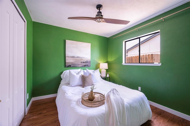 bedroom featuring ceiling fan, a closet, baseboards, and wood finished floors