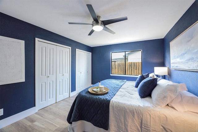 bedroom with a ceiling fan, wood finished floors, baseboards, and two closets