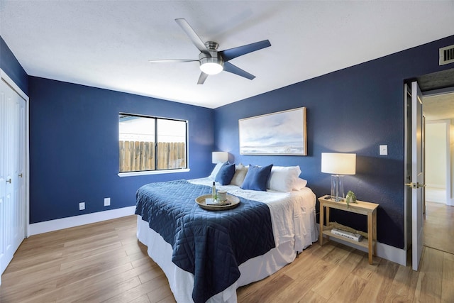 bedroom with visible vents, baseboards, wood finished floors, and a ceiling fan