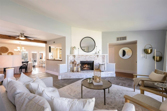 living area with visible vents, a brick fireplace, baseboards, lofted ceiling, and ceiling fan with notable chandelier