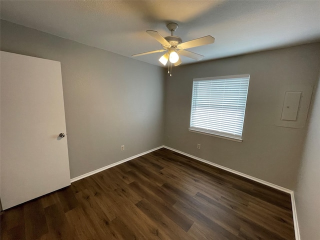 unfurnished room featuring electric panel, baseboards, dark wood finished floors, and a ceiling fan