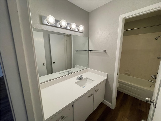 full bathroom with  shower combination, a textured wall, vanity, and wood finished floors