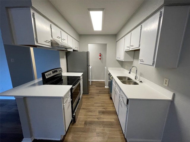 kitchen with wood finished floors, light countertops, stainless steel appliances, under cabinet range hood, and a sink