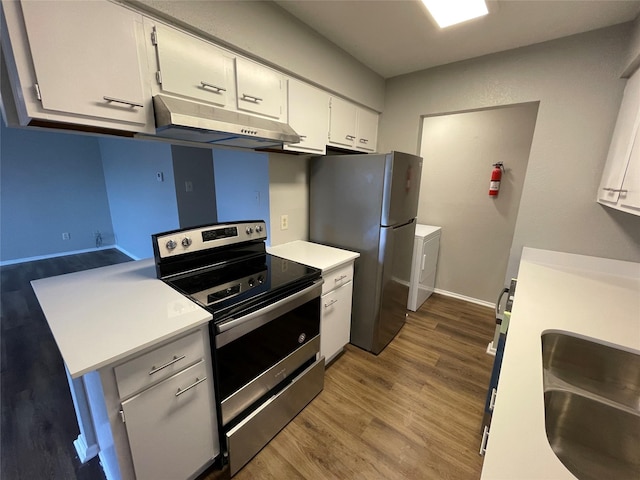 kitchen with appliances with stainless steel finishes, wood finished floors, light countertops, under cabinet range hood, and white cabinetry