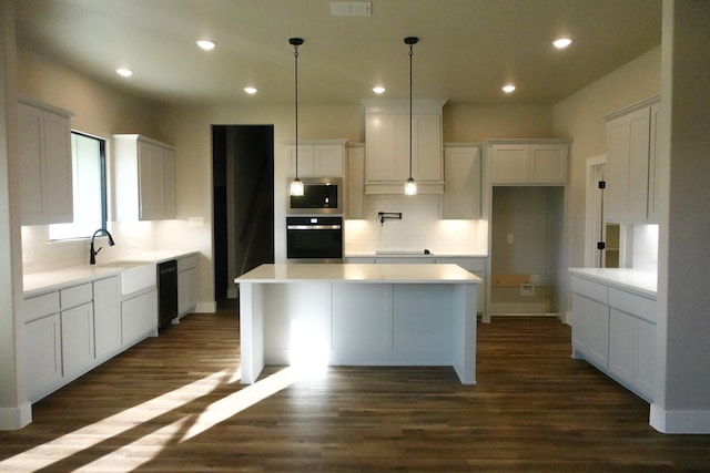 kitchen with oven, white cabinetry, a center island, dark wood-style floors, and stainless steel microwave