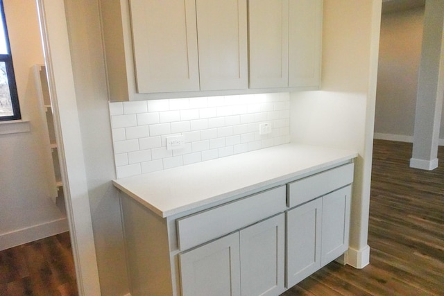 kitchen with dark wood-style floors, tasteful backsplash, baseboards, and light countertops