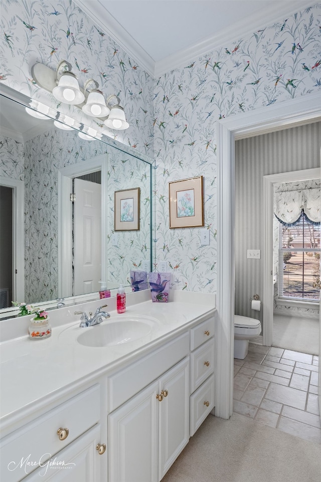 bathroom with crown molding, toilet, vanity, and wallpapered walls