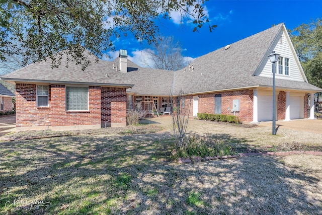 back of property with a yard, brick siding, a chimney, and a shingled roof