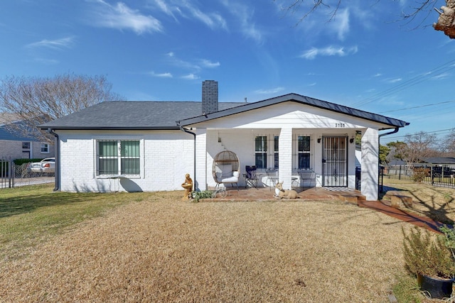 back of property with a lawn, a chimney, fence, a porch, and brick siding