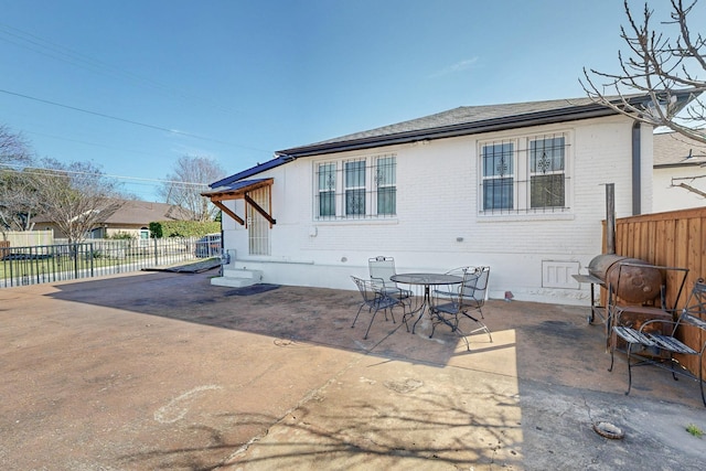 back of house with a patio area, brick siding, fence, and outdoor dining area