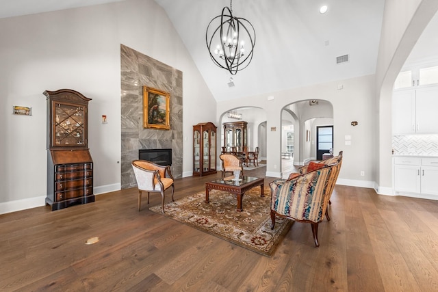 living area with high vaulted ceiling, wood finished floors, visible vents, and a premium fireplace