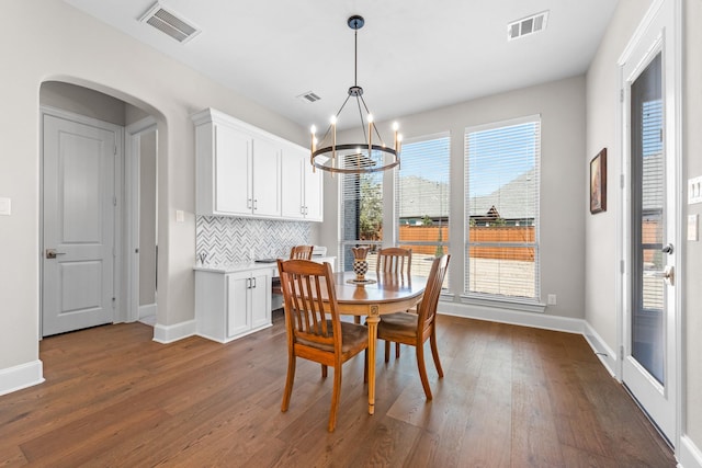 dining space with visible vents, arched walkways, and dark wood-type flooring