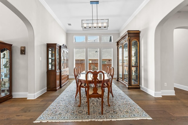 dining space with arched walkways, ornamental molding, and dark wood-style flooring