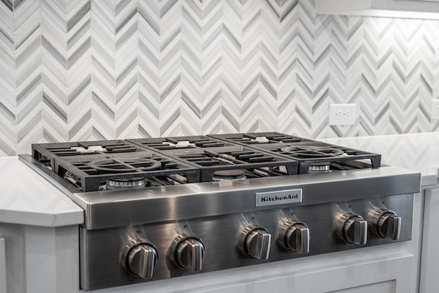 interior details with backsplash, range, and stainless steel gas stovetop