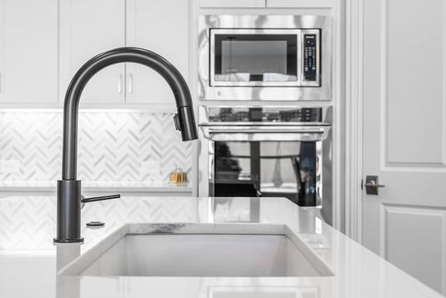 interior details with light countertops, appliances with stainless steel finishes, a sink, and white cabinets