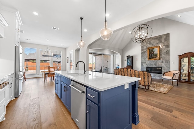 kitchen with blue cabinets, stainless steel appliances, a sink, visible vents, and a high end fireplace