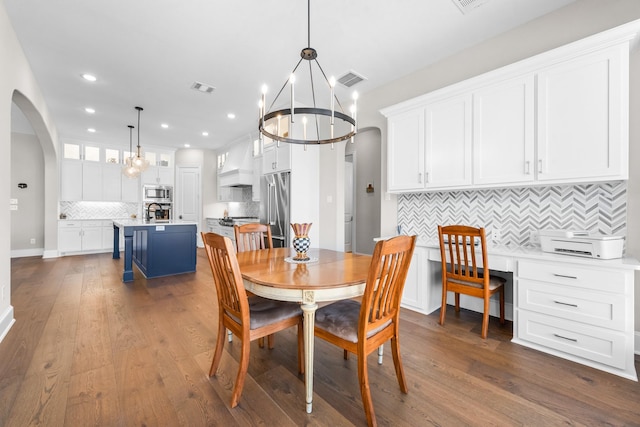 dining room with arched walkways, dark wood-type flooring, visible vents, and recessed lighting